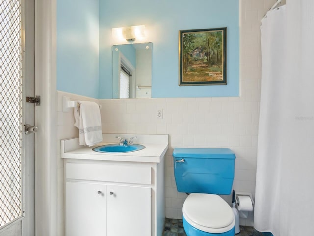 bathroom with vanity, tile walls, toilet, and a wainscoted wall