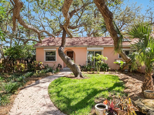 single story home with stucco siding, a tile roof, a front yard, and fence