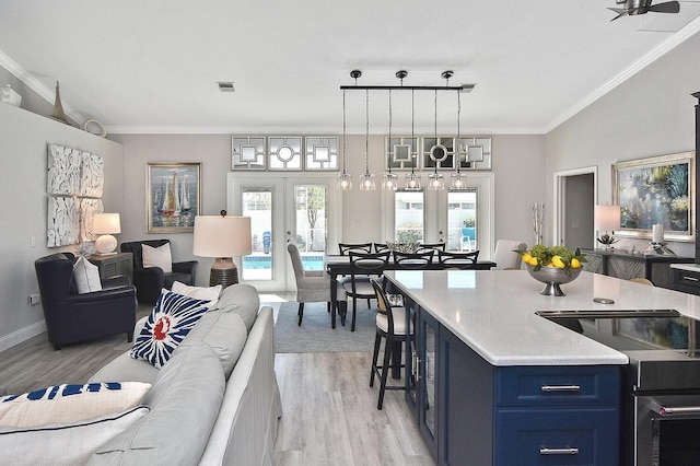 kitchen with ornamental molding, light wood-style floors, french doors, blue cabinets, and open floor plan