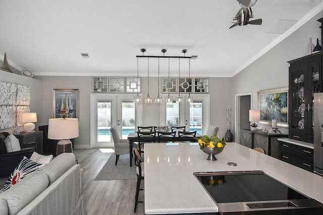 kitchen featuring crown molding, open floor plan, a breakfast bar area, light countertops, and french doors