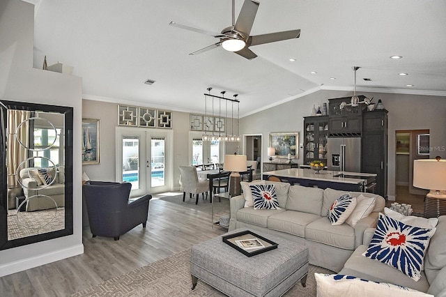 living room featuring light wood-type flooring, visible vents, ornamental molding, french doors, and vaulted ceiling