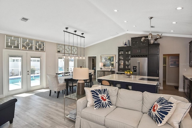 living area with light wood finished floors, visible vents, crown molding, lofted ceiling, and french doors