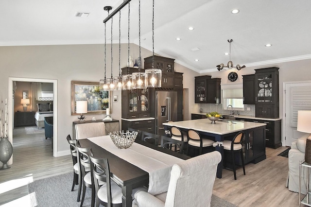 dining area featuring visible vents, light wood-style flooring, recessed lighting, vaulted ceiling, and crown molding