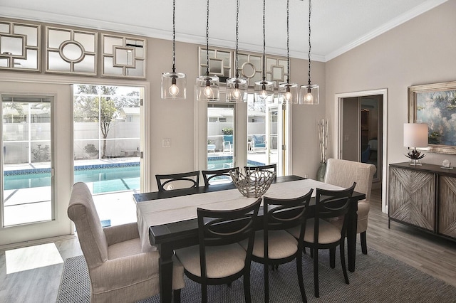 dining room featuring wood finished floors, ornamental molding, and vaulted ceiling