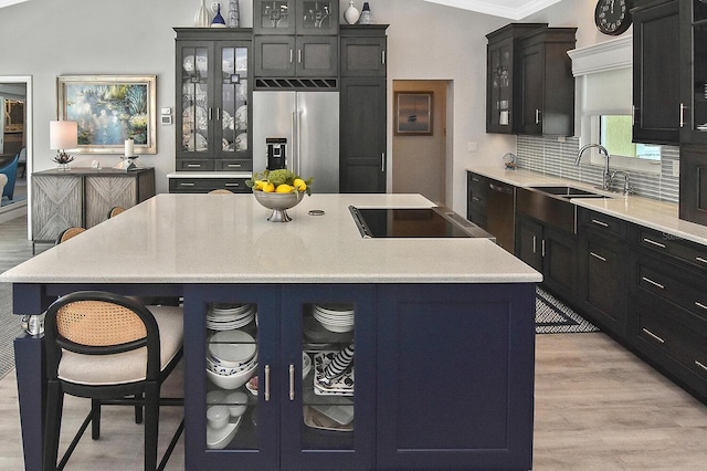 kitchen with a sink, glass insert cabinets, light wood finished floors, and high end refrigerator