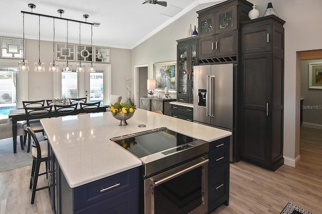 kitchen featuring light countertops, lofted ceiling, ornamental molding, a kitchen breakfast bar, and appliances with stainless steel finishes