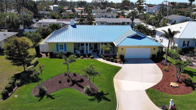 view of front of home featuring a front lawn, concrete driveway, stucco siding, metal roof, and a garage