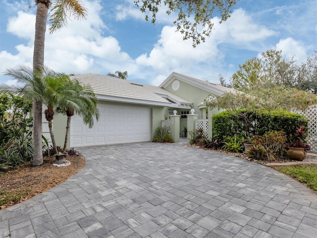 view of front of home featuring decorative driveway, a gate, an attached garage, and stucco siding