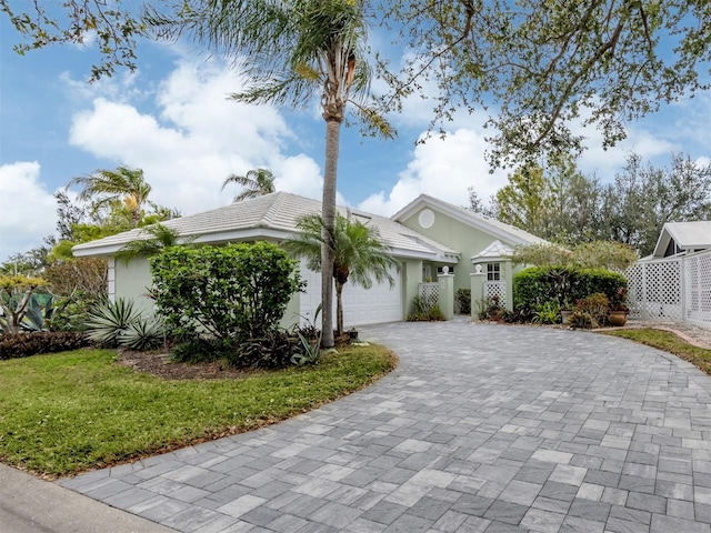 view of front of house featuring decorative driveway, a garage, and stucco siding