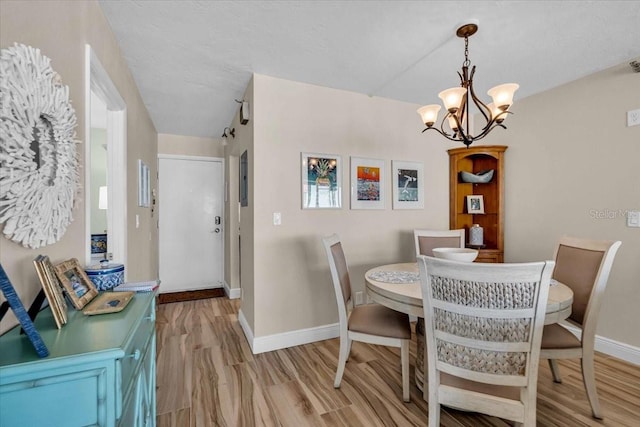 dining area featuring light wood-style floors, baseboards, and a notable chandelier