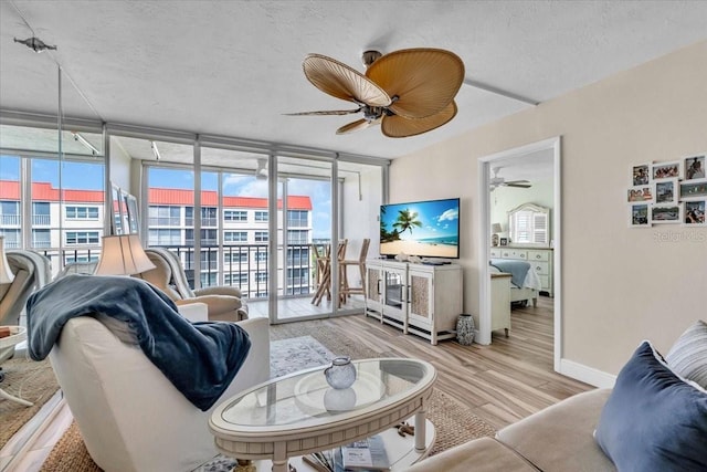 living room featuring a ceiling fan, floor to ceiling windows, wood finished floors, and baseboards