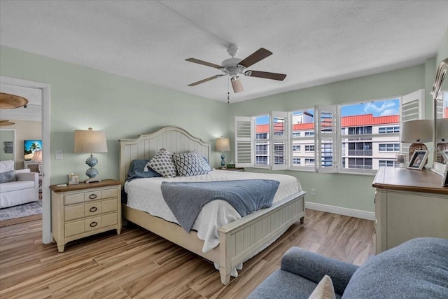 bedroom with a ceiling fan, light wood-type flooring, and baseboards