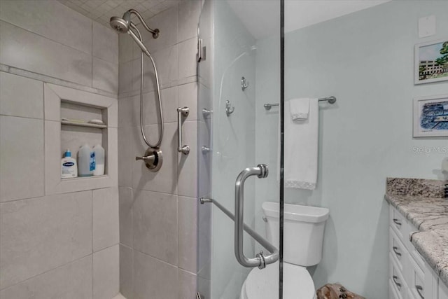 bathroom with a shower stall, vanity, and toilet