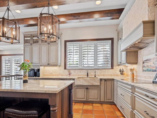 kitchen with an inviting chandelier, light stone counters, a sink, black electric cooktop, and backsplash