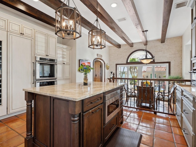 kitchen with visible vents, a notable chandelier, cream cabinetry, stainless steel appliances, and light stone counters