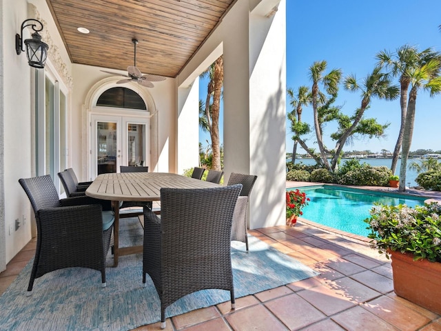 view of patio featuring a water view, ceiling fan, outdoor dining area, an outdoor pool, and french doors