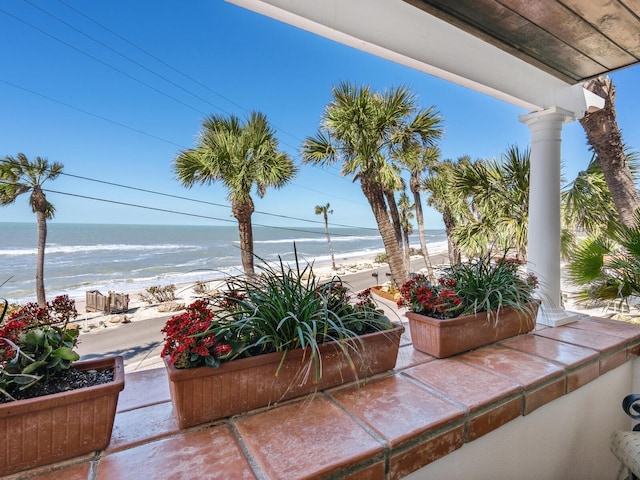 view of patio featuring a water view and a beach view