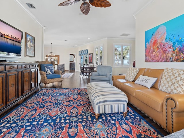 living area with crown molding, ceiling fan with notable chandelier, and visible vents