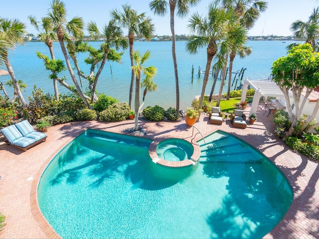view of swimming pool featuring a patio area, a pool with connected hot tub, and a water view