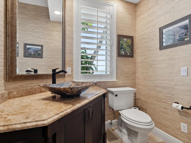 bathroom with toilet, vanity, and tile walls