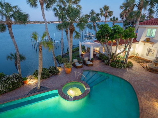 view of swimming pool featuring a patio area, a pool with connected hot tub, a water view, and a pergola