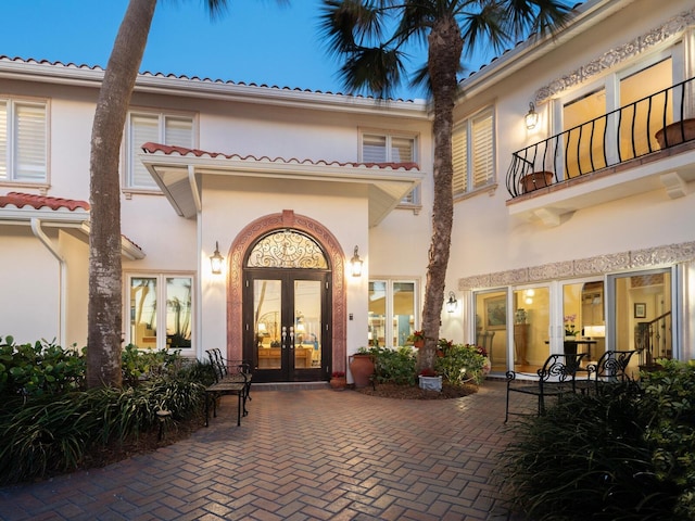 back of house with a balcony, french doors, and stucco siding