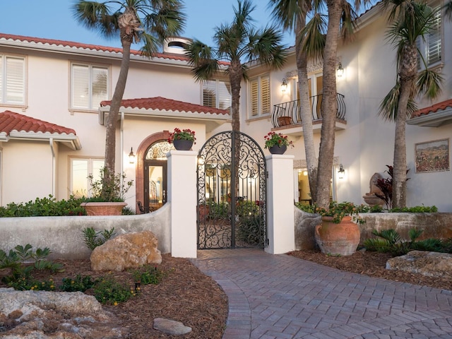 view of front of property with a balcony, stucco siding, and a tiled roof