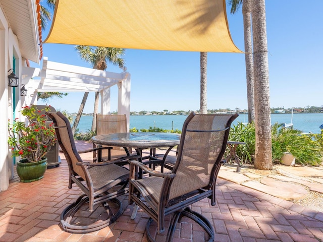 view of patio with a water view, outdoor dining area, and a pergola