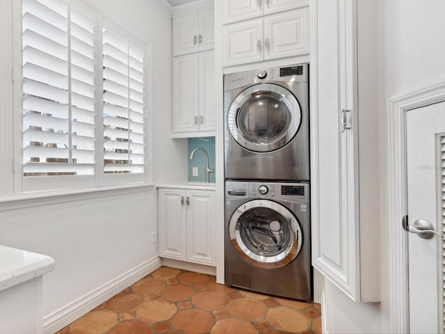 clothes washing area featuring cabinet space, stacked washing maching and dryer, and a sink