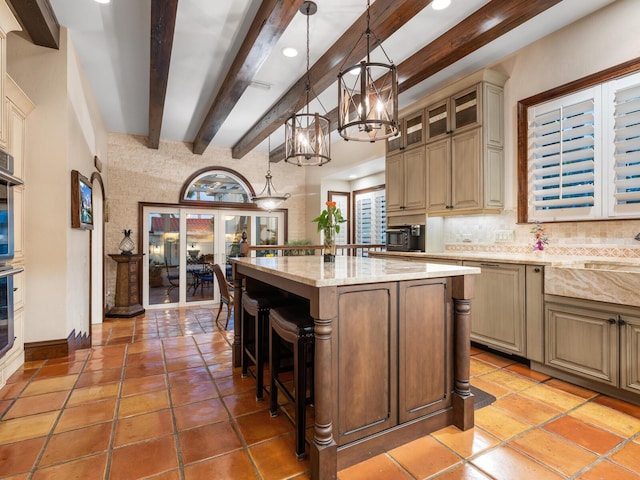 kitchen with a kitchen breakfast bar, an inviting chandelier, backsplash, a kitchen island, and beamed ceiling