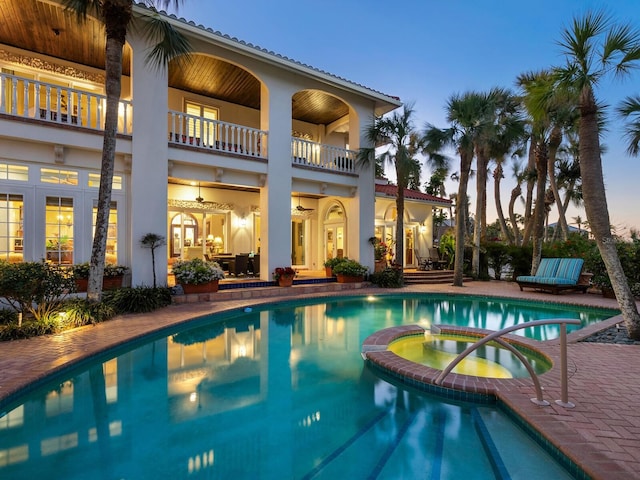 pool at dusk with a pool with connected hot tub, a patio, and french doors