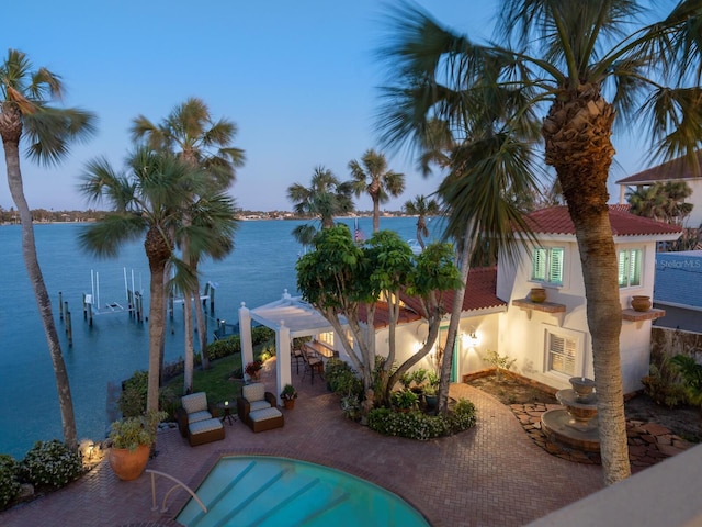 view of swimming pool with a patio area, a water view, and a pergola