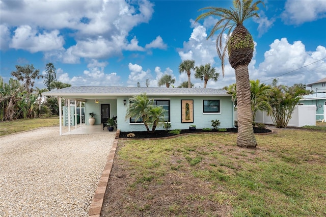 single story home featuring an attached carport, gravel driveway, and a front lawn