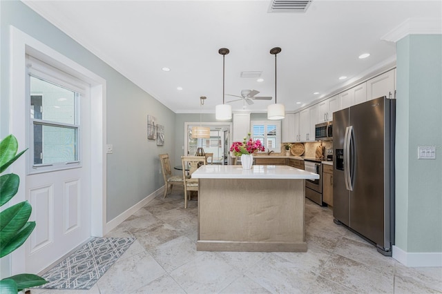 kitchen featuring visible vents, stainless steel appliances, white cabinets, crown molding, and a center island