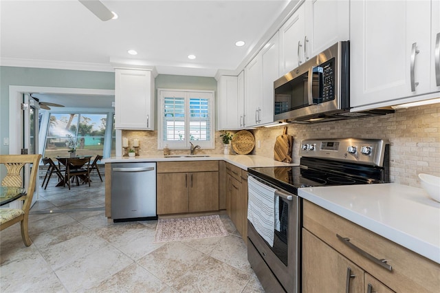 kitchen featuring a sink, stainless steel appliances, white cabinets, light countertops, and decorative backsplash