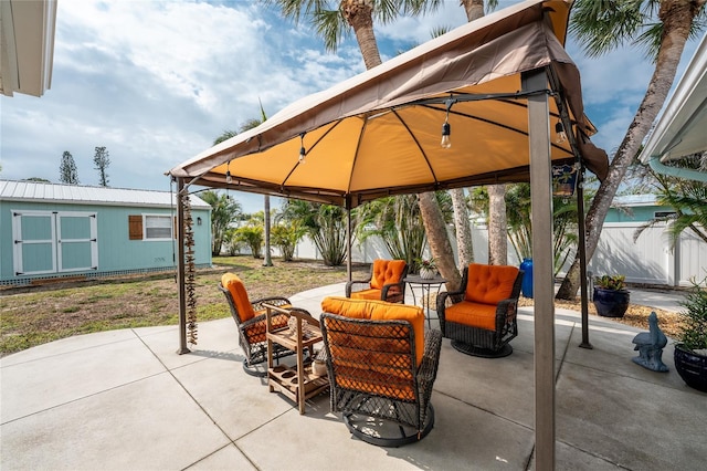 view of patio / terrace featuring a gazebo, an outdoor hangout area, an outdoor structure, and fence