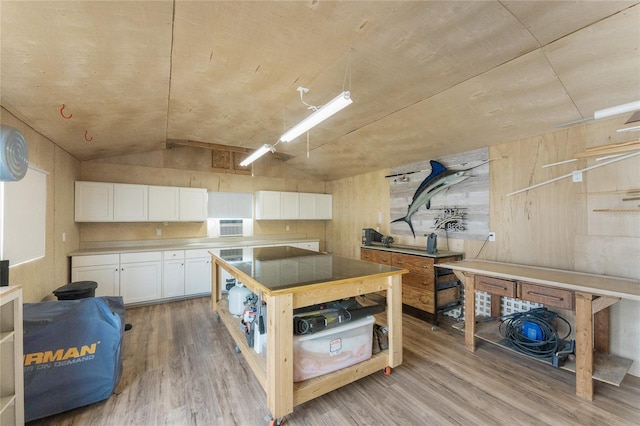 kitchen featuring light wood-style floors, light countertops, vaulted ceiling, and white cabinetry