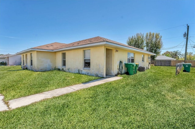 view of home's exterior with stucco siding, cooling unit, a yard, and fence