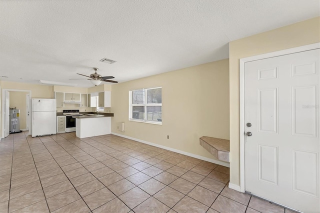 kitchen featuring a ceiling fan, visible vents, a peninsula, freestanding refrigerator, and range with electric stovetop