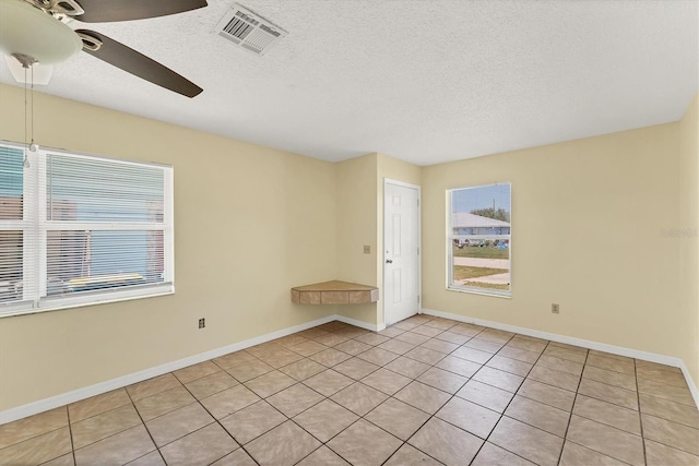 unfurnished room featuring baseboards, a ceiling fan, visible vents, and a textured ceiling