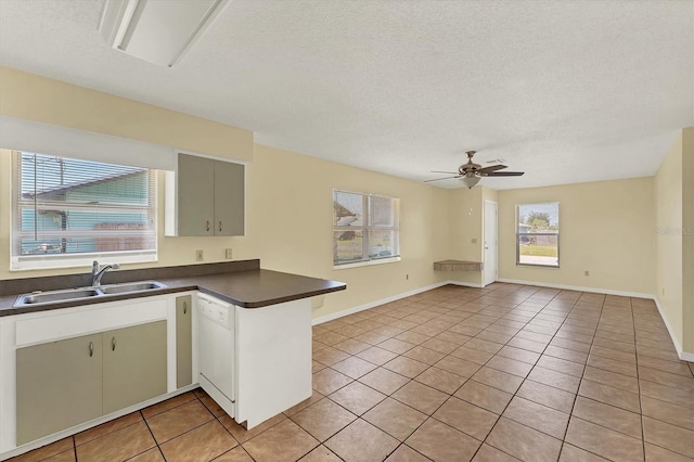 kitchen with dark countertops, light tile patterned floors, white dishwasher, a ceiling fan, and a sink