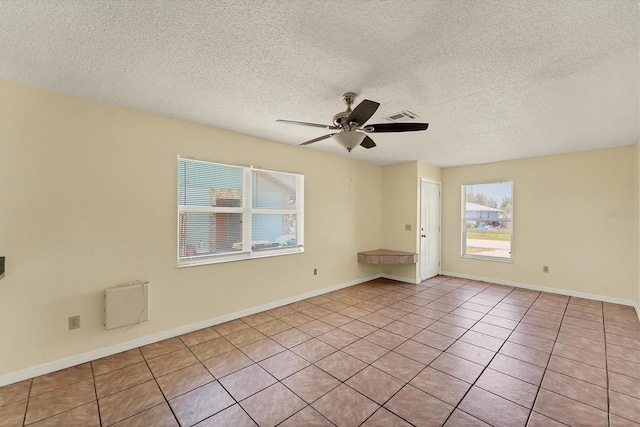 spare room featuring visible vents, a textured ceiling, light tile patterned floors, baseboards, and ceiling fan