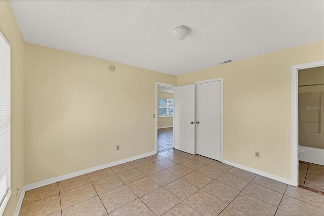 unfurnished bedroom with light tile patterned floors, baseboards, visible vents, and a closet