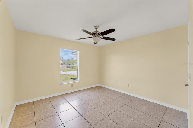 empty room with light tile patterned flooring, a ceiling fan, and baseboards