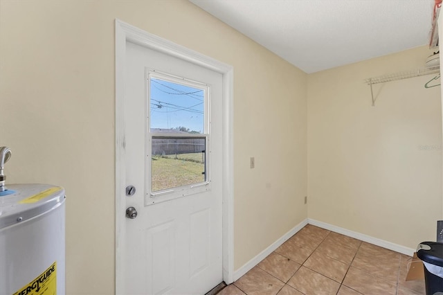 laundry area featuring light tile patterned flooring, gas water heater, and baseboards