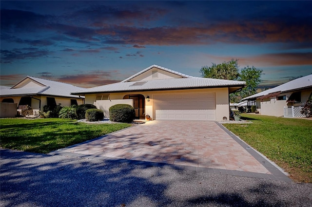 view of front facade featuring decorative driveway, a front yard, an attached garage, and a tile roof