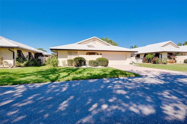 ranch-style home featuring a garage, a front lawn, driveway, and stucco siding