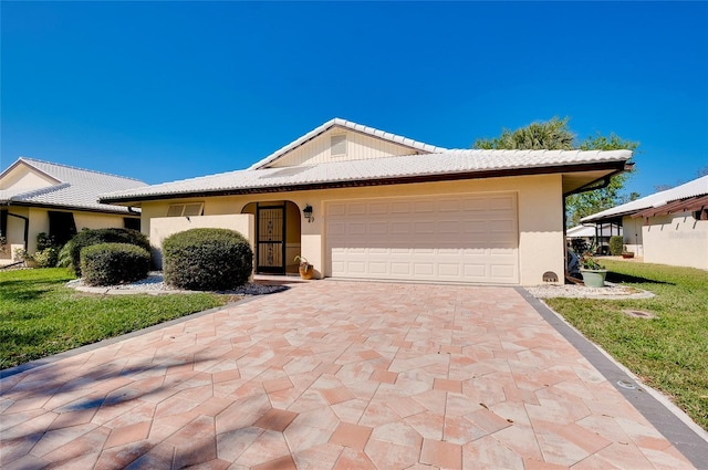 ranch-style house with a tile roof, decorative driveway, a garage, and stucco siding