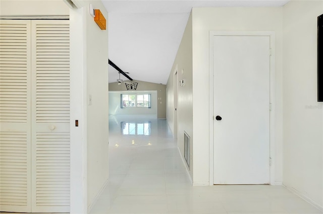 corridor featuring tile patterned floors, visible vents, baseboards, and lofted ceiling