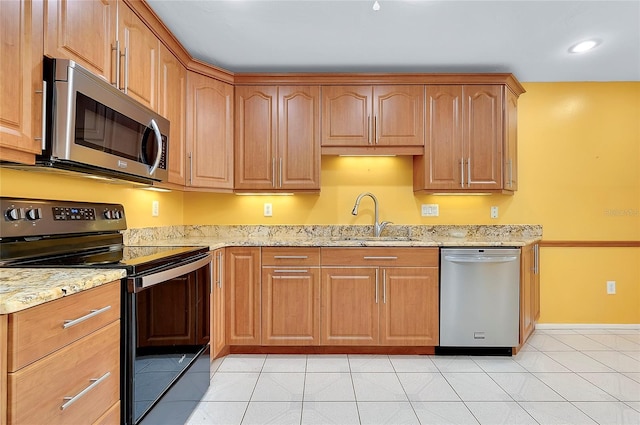 kitchen with a sink, light tile patterned flooring, light stone countertops, and stainless steel appliances